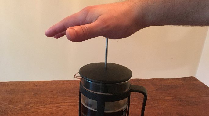 将金属棒推入壶中，制作法式压滤咖啡